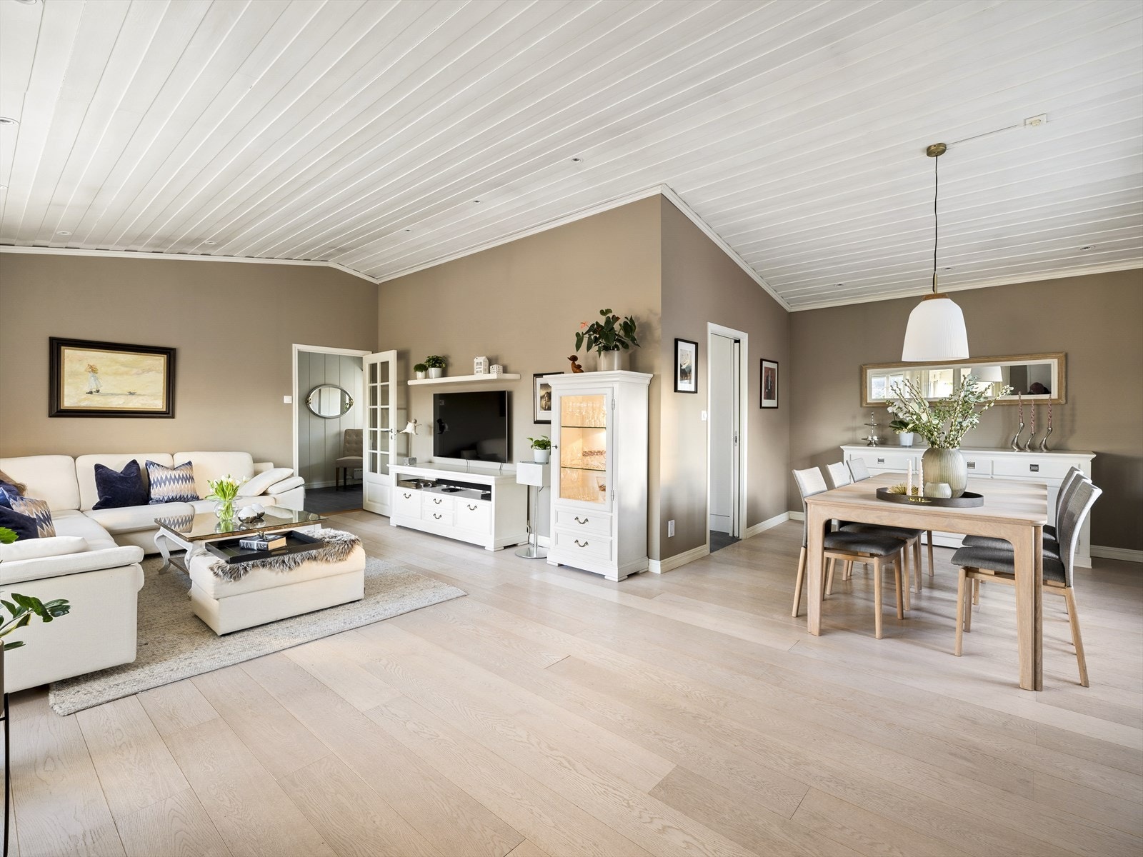 Stor og luftig stue med moderne preg. Ekstra takhøyde, kombinert med godt daglys gir en god romfølelse. Parkett på gulv, malte vegger, panel og spotter i tak. Galleribilde