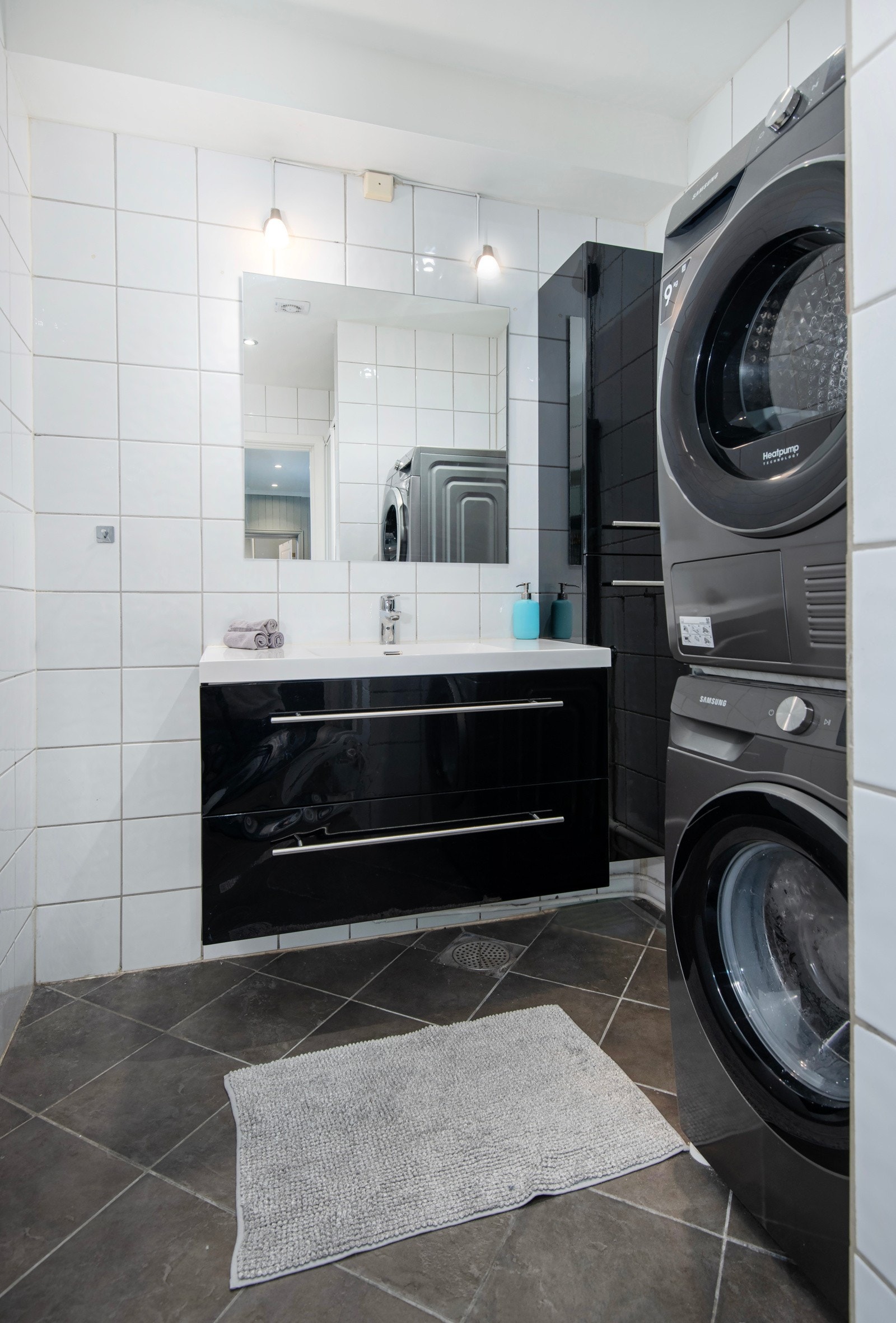 Baderomsinnredningen har mørke skuffefronter i høyglans, og der er speil og belysning over helstøpt servant. Galleribilde