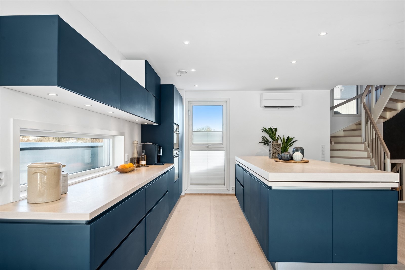 Benkeplate over kjøkkenøy skjuler induksjonstoppen - perfekt for et ryddig kjøkken, samt praktisk da benkeplaten fungerer som ekstra spisebord når den er trukket ut. Galleribilde