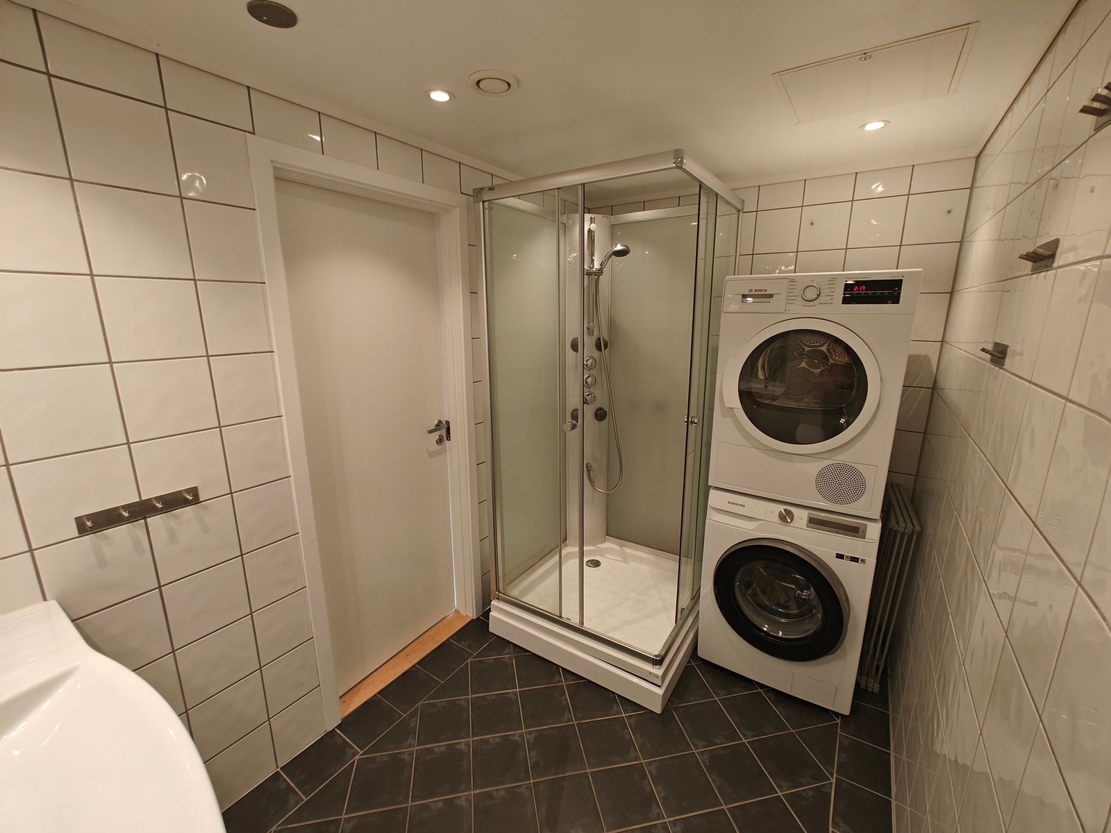 Dusj kabinett med vaskemaskin samt tørketrommel på badet. Galleribilde