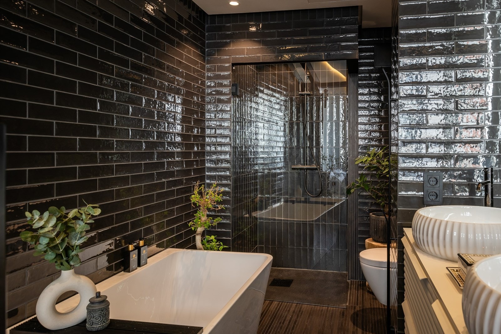 Nedsenket dusjsone med regnfallsduj og glassvegger. Badekar og doble servanter samt glasstak over deler av rommet Galleribilde