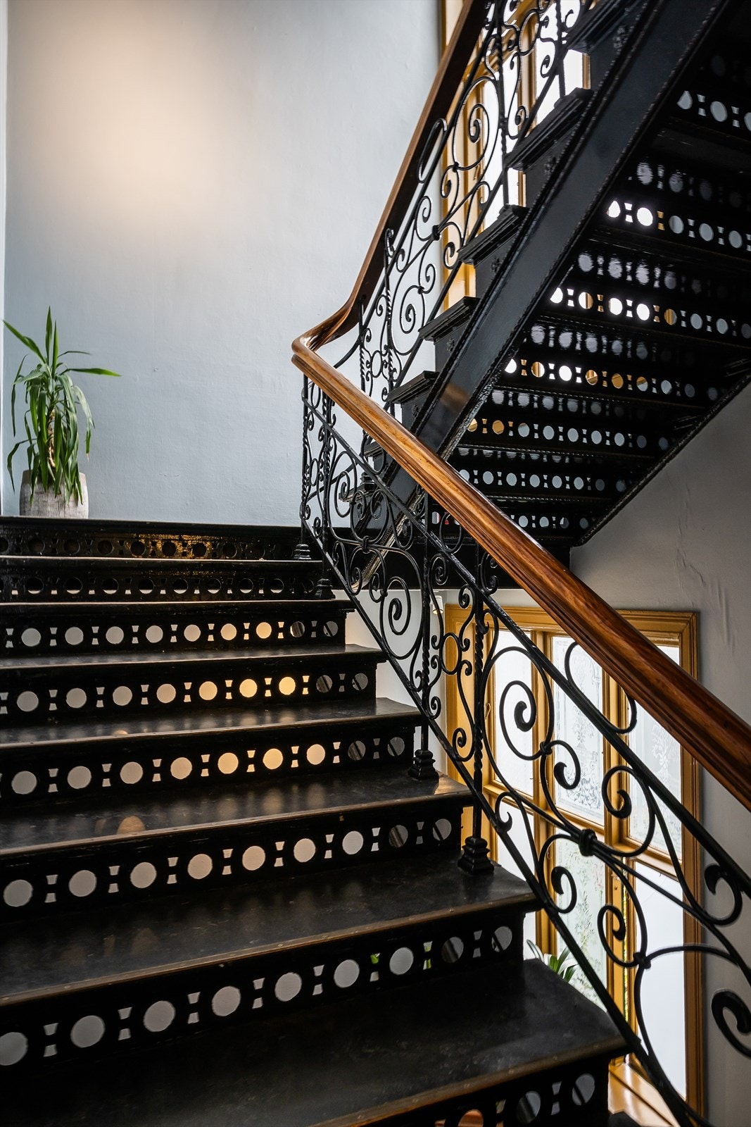 Flott trappeløp med smijerns rekkverk, flislagte repos og store vinduer Galleribilde