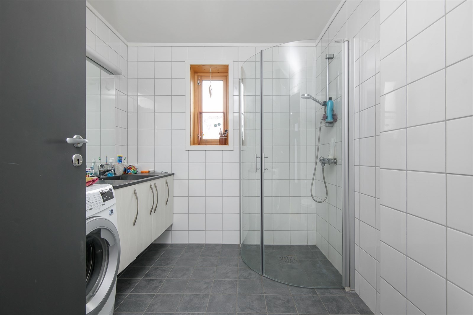 Tidløst og funksjonelt bad/wc med dusjhjørne og servantinnredning. Opplegg for vaskemaskin. Galleribilde
