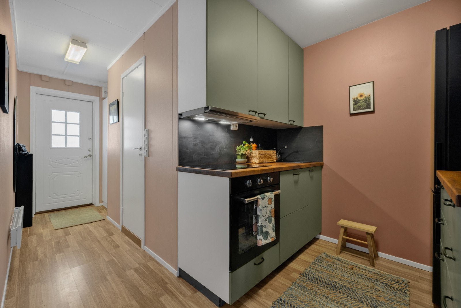 Kjøkkenet har et moderne uttrykk med slette fronter i grønt, sorte håndtak og benkeplater i heltre Galleribilde