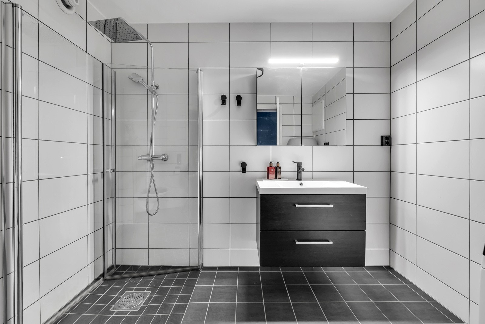 Pent og romslig bad som er flislagt på gulv og vegger Galleribilde