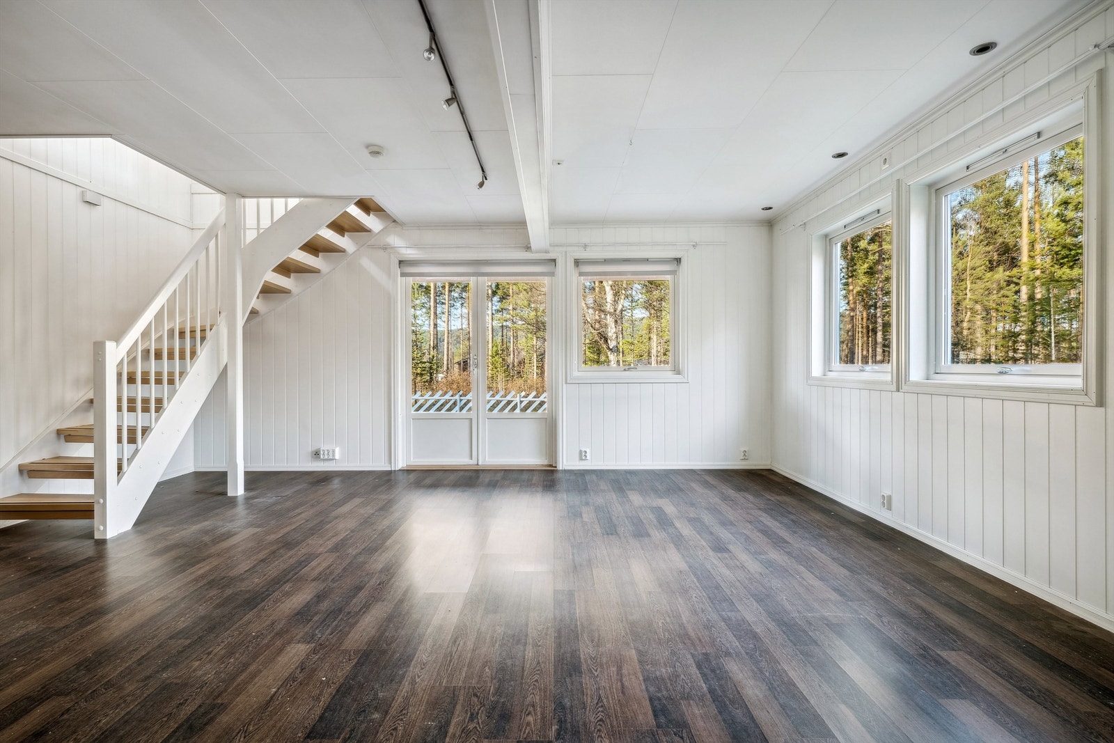 Stuen har hvitmalt panelplater på veggene og mørk laminat på gulvet. Galleribilde