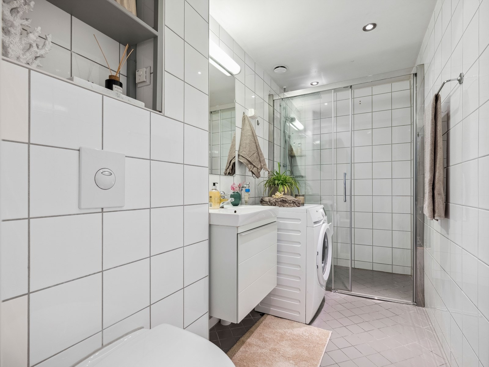 Lekkert og stilrent baderom fra 2010. Badet består av fliser på gulv og vegger. Belysningen er integrert i taket. Det er i tillegg opplegg for vaskemaskin, som også medfølger salget. Galleribilde