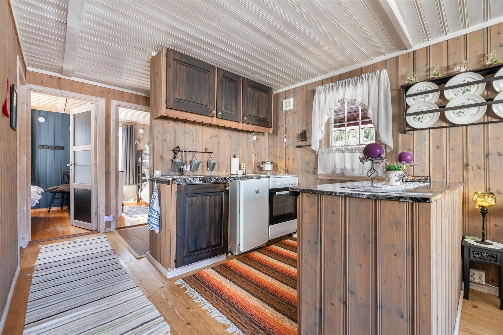 Kjøkkeninnredningen har over- og underskap med profilerte fronter. Benkeplate i heltre med pålagt folie og nedfelt kum. Galleribilde