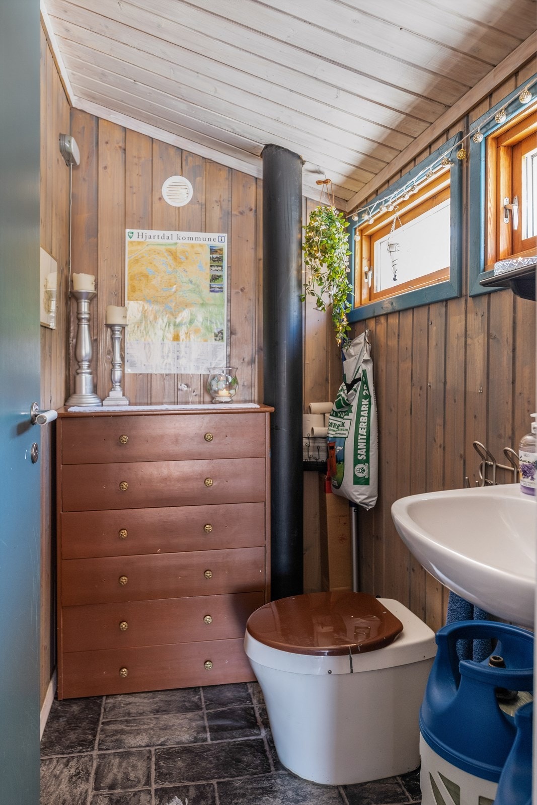 Et enkelt toalettrom hvor det er montert snurredo med kammerløsning og veggmontert håndvask. Galleribilde