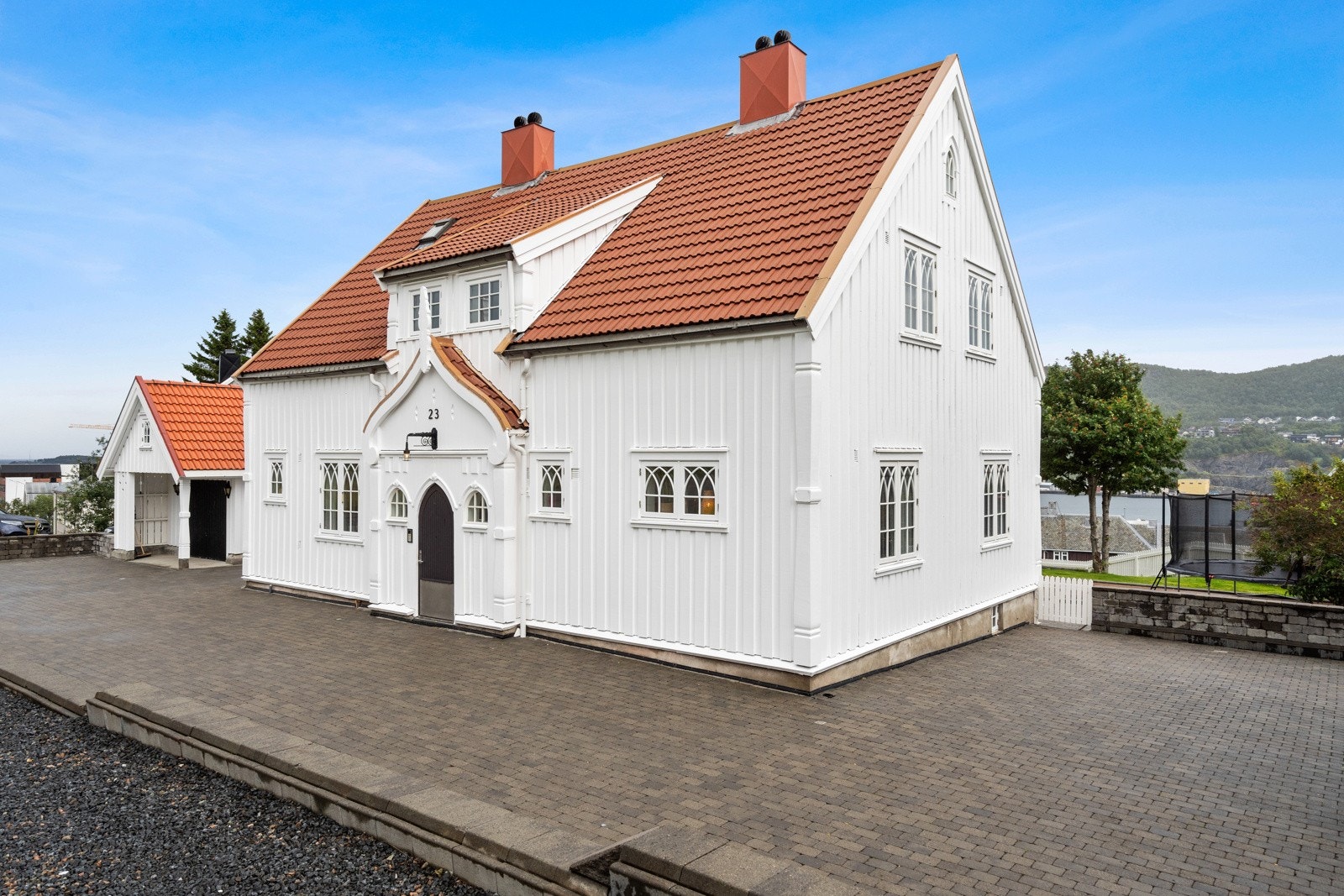 Pent opparbeidet uteomåde med brostein, murer, plattinger og plen. Galleribilde