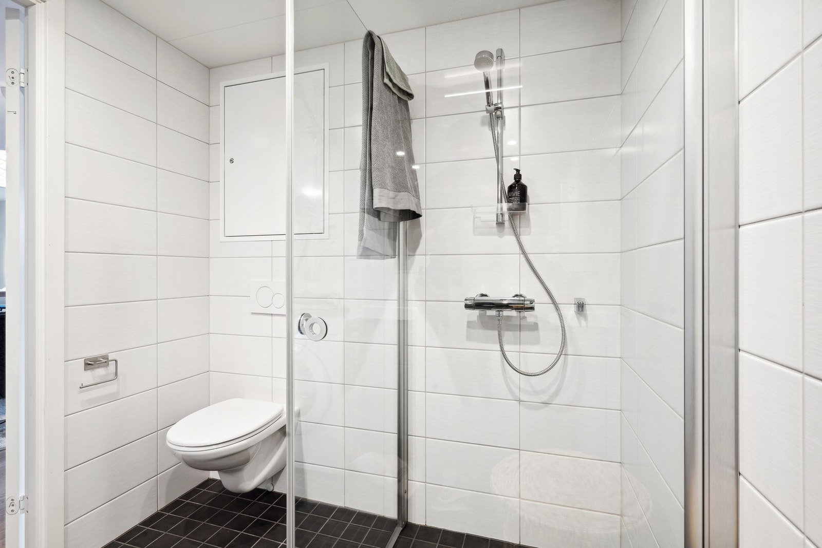 På badet har man dusjhjørne med innfellbare glassdører, vegghengt toalett, opplegg for vaskemaskin og downlights i tak. Galleribilde