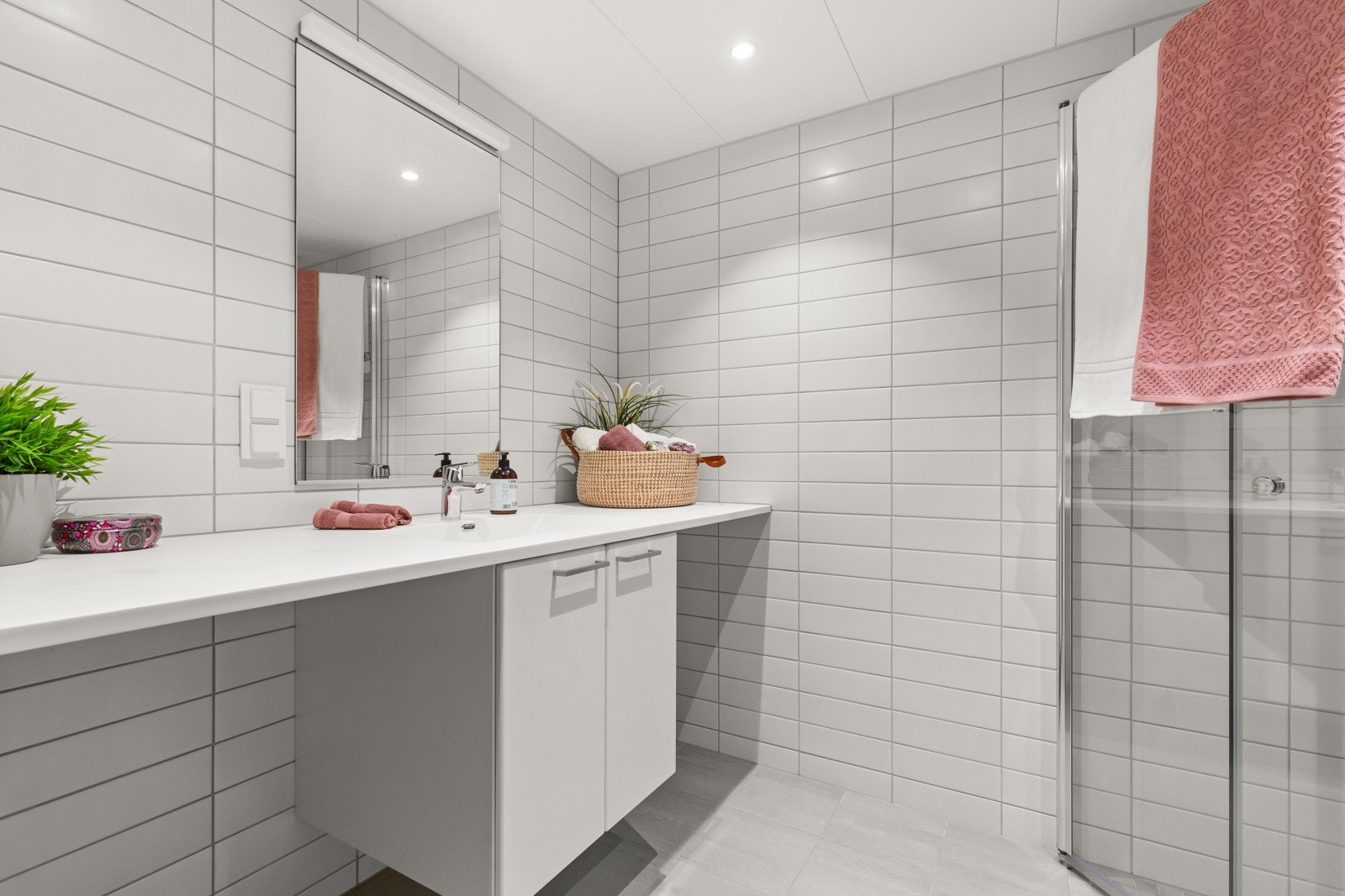 Badet er utstyrt med nedsenket dusjsone med innfellbare glassdører, vegghengt wc, servant med romslig servantskap under, speil med lys og opplegg for vaskemaskin/tørketrommel. Galleribilde