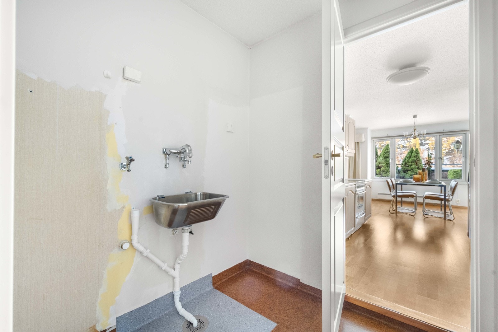 Praktisk vaskerom med belegg på gulv og tapet på veggene. Vaskerommet har adkomst både fra gangen og fra kjøkkenet Galleribilde