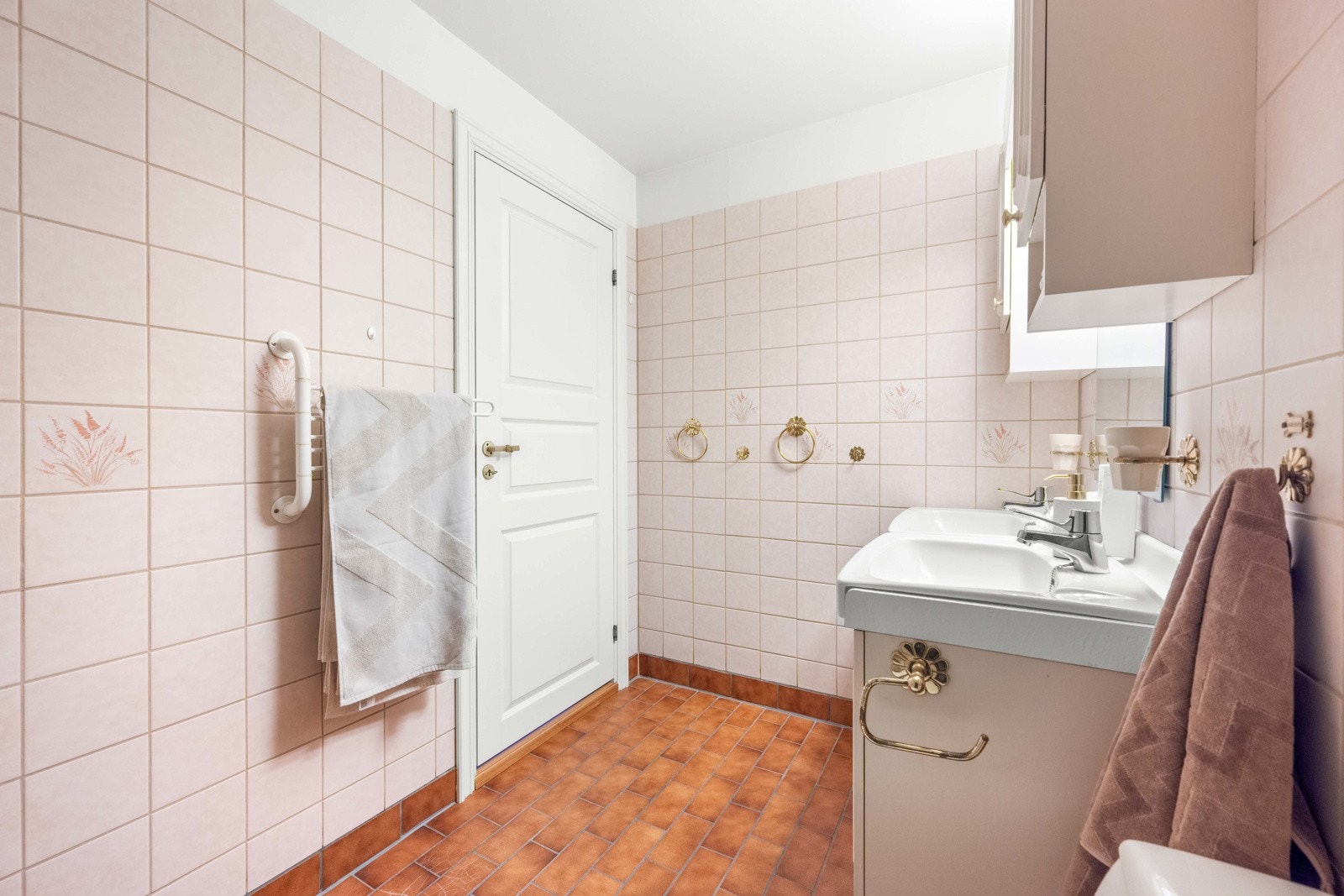 Badet er innredet med vegghengt servantinnredning med dører og dobbel ovenpåliggende servant. Det er speil med overlys og stikkontakt på veggen over servanten. Videre har badet gulvstående toalett og dusjkabinett Galleribilde