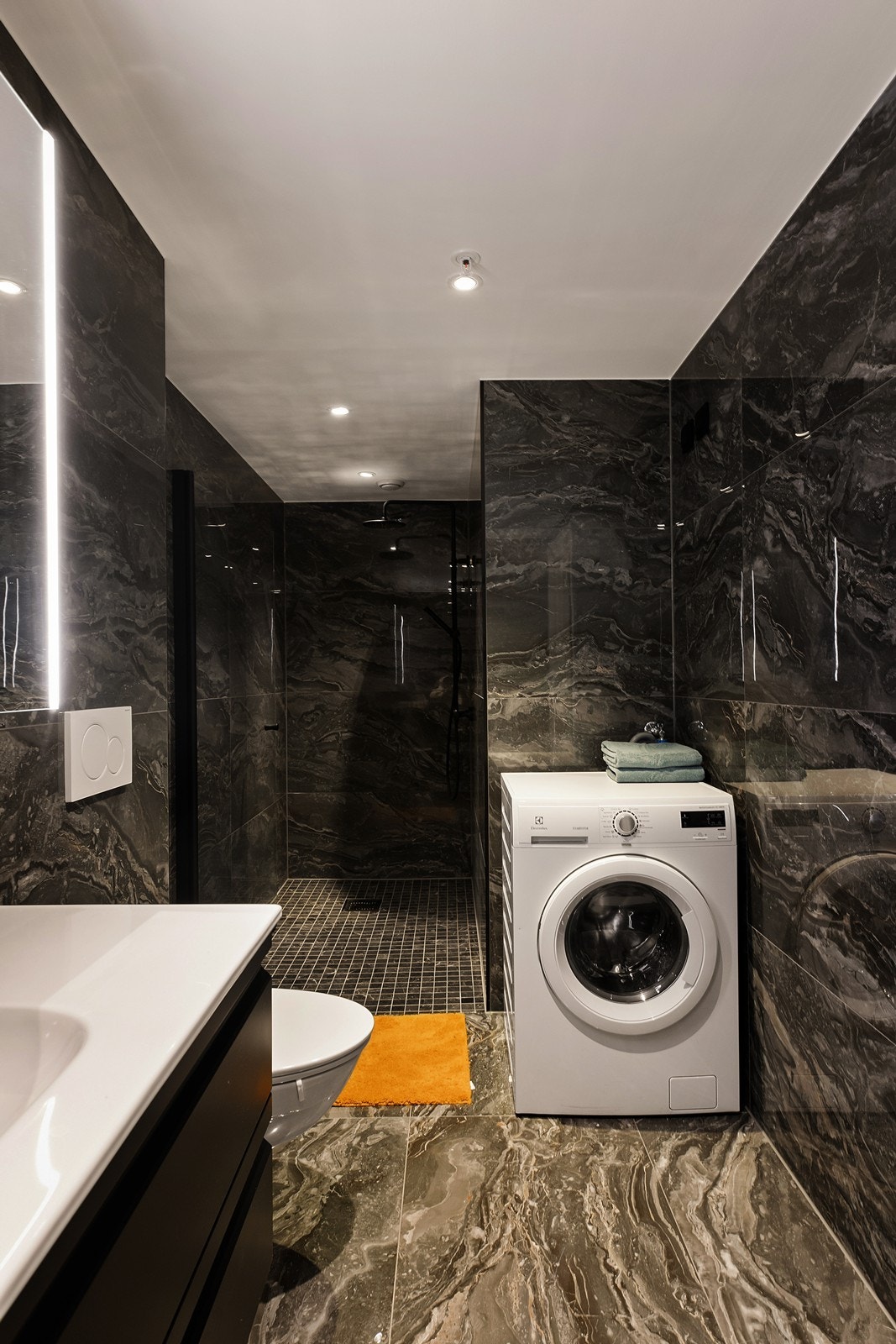 Lekkert bad fra 2022 med dusjnisje, servantinnredning, wc og opplegg for vaskemaskin Galleribilde