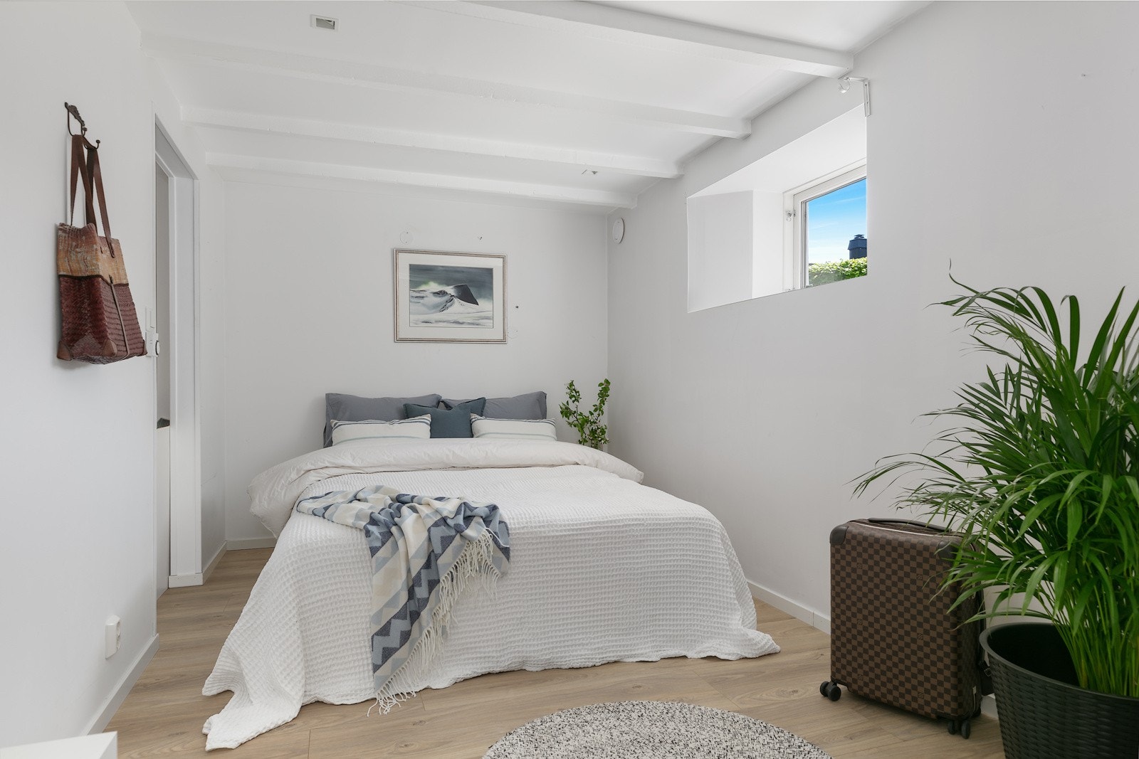 Soverommet i kjelleren er lyst og hyggelig med hvitmalte vegger og tak, og inngang til garderoberom Galleribilde