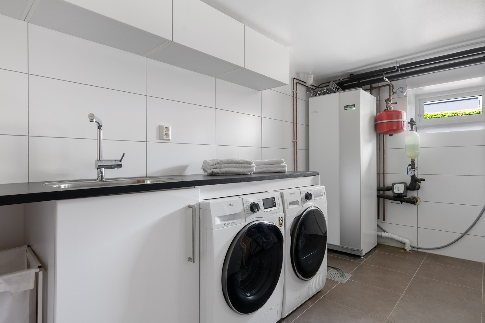 Separat vaskerom med benkeplate i laminat og underskap, høyskap, overskap, opplegg for vaskemaskin Galleribilde