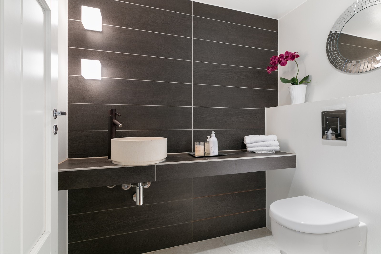 Toalett i kjeller med flislagt gulv med vannbåren gulvvarme, og vegger med fliser og glatte malte overflater Galleribilde