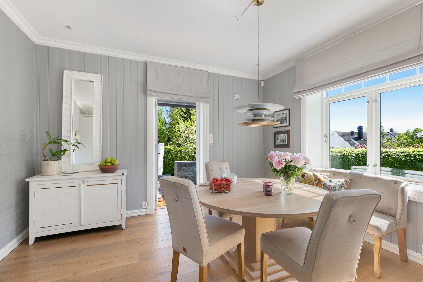 En lys og hyggelig spisestue med dør ut til overbygd terrasse og trapp ned til terrassen og hagen Galleribilde