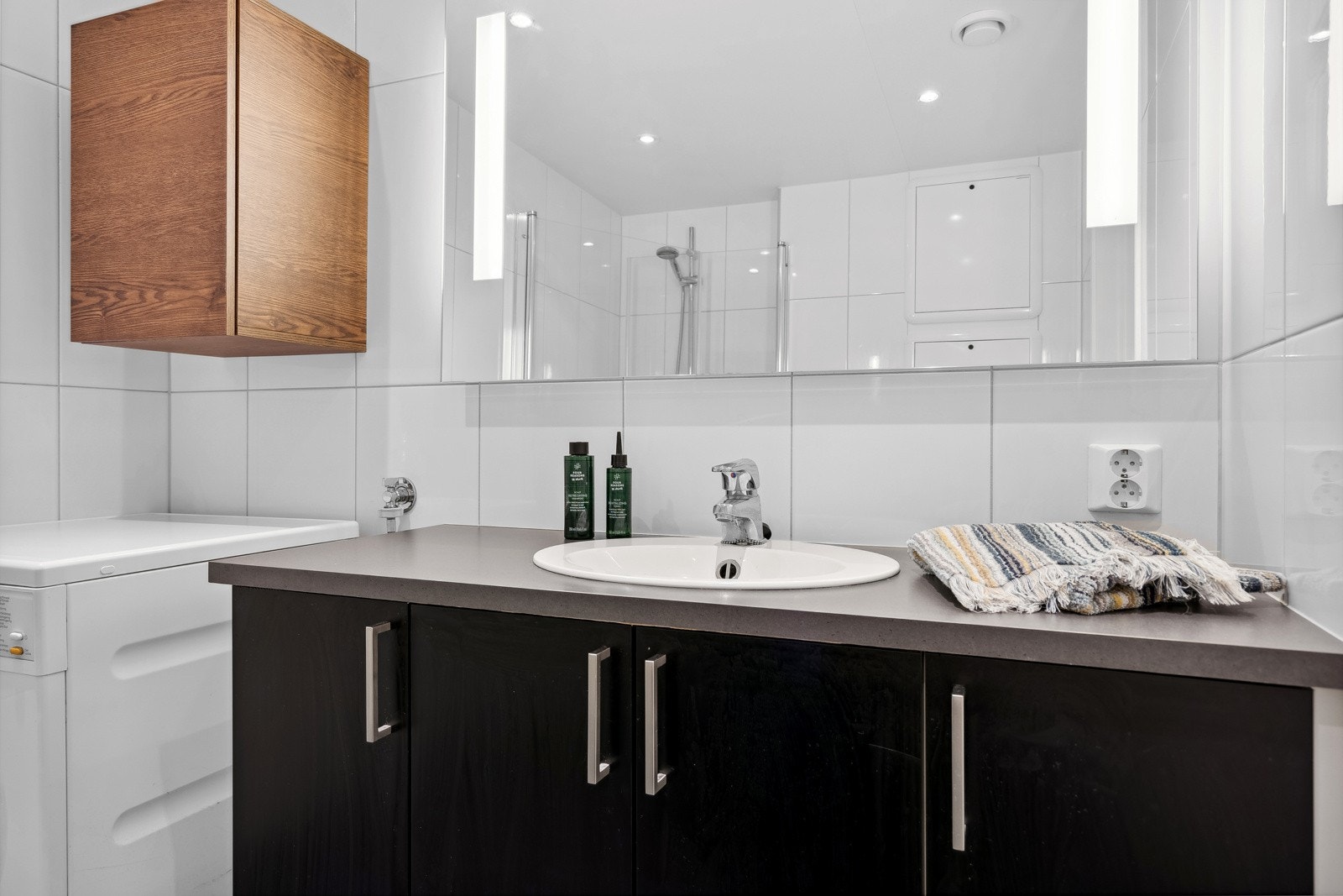 Lekkert bad utstyrt med vegghengt toalett, dusjhjørne i glass og servantinnredning med speil. Galleribilde