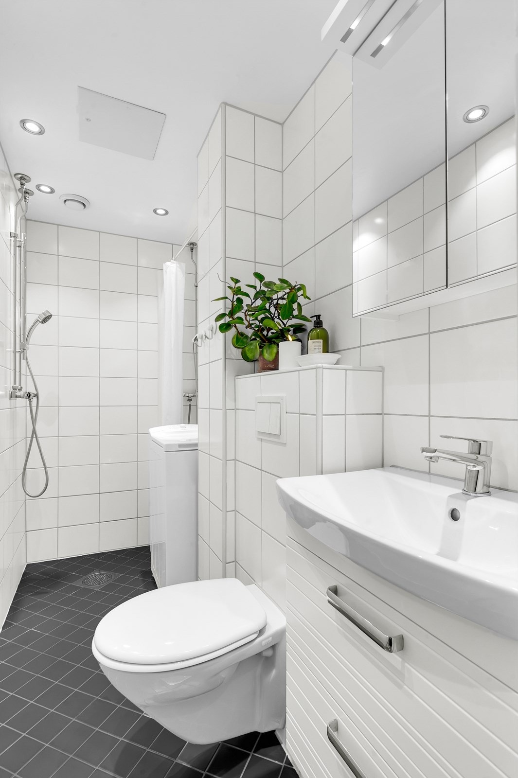 Baderommet er utstyrt med servant med innredning, vegghengt toalett, opplegg for vaskemaskin og dusjnisje. Det er varme i gulv Galleribilde