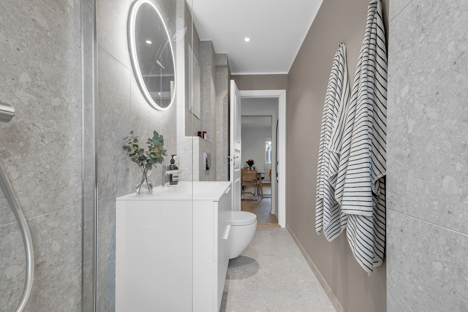 Baderomsinnredning bestående av benkeskap, speil og belysning over servant samt stort dusjhjørne Galleribilde