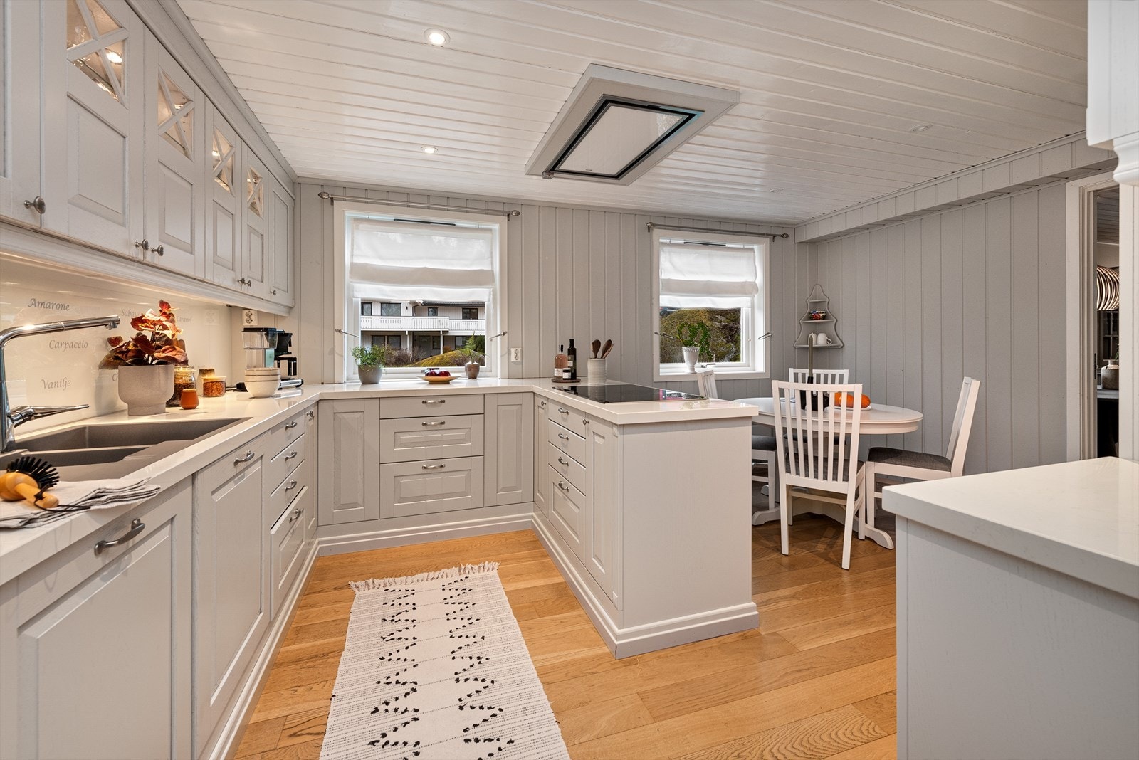 Takhøy kjøkkeninnredning og heltre eikefronter. Det er glass/sprosser i 4 overskapdører. Det er en benkeplate i komposittmateriale og et underlimt kompositt benkebeslag. Ventilator med lys er montert i himling og det er komfyrvakt over kokesonen. Galleribilde