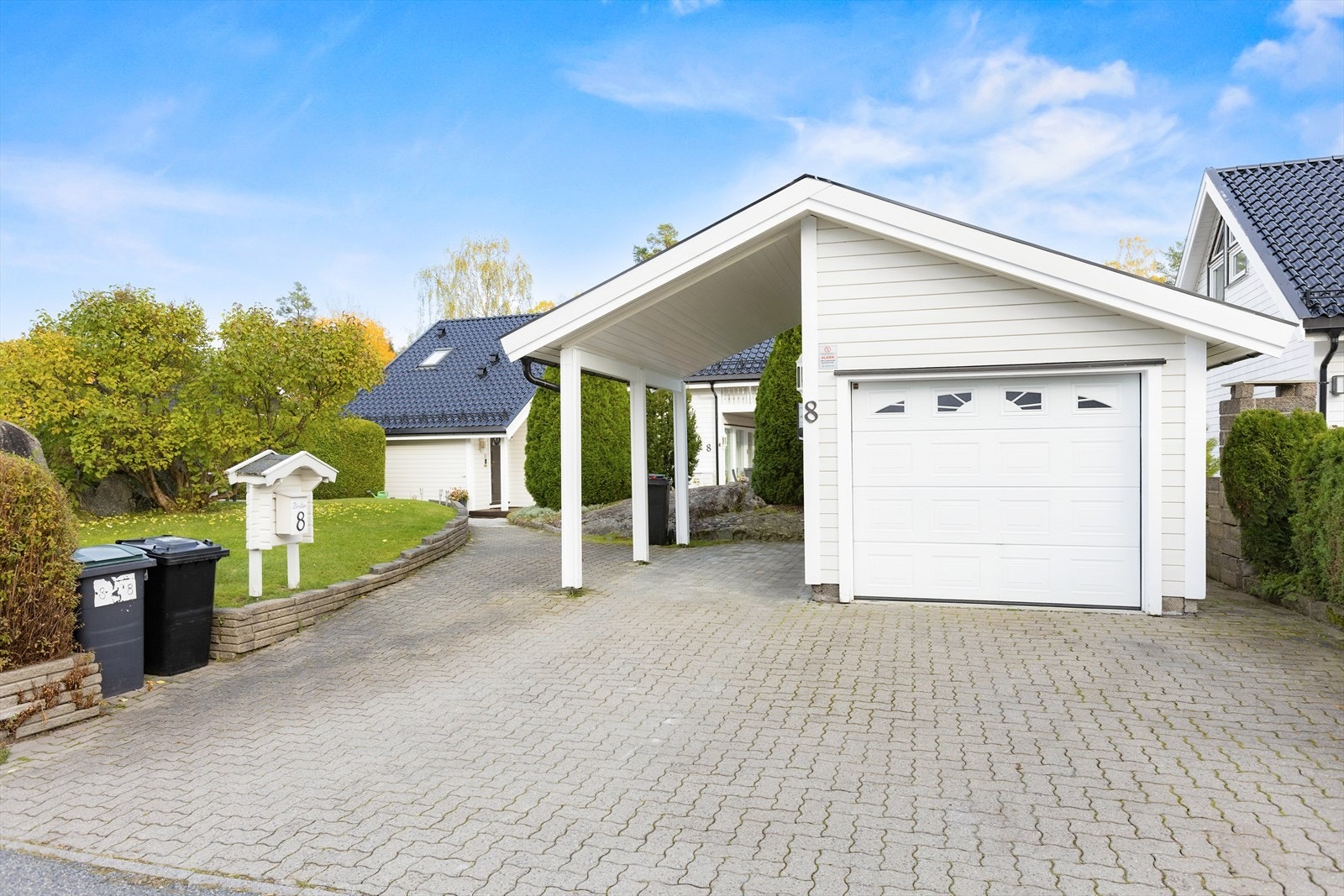 Garasjebygget består av garasje for bil med tilliggende carport med tre åpne sider. Garasjen har et bruttoareal på ca. 22 m² og carporten et bebygd areal på ca. 13m². Installert el-bil lader på utvendig garasjevegg. Motorisert garasjeport. Galleribilde