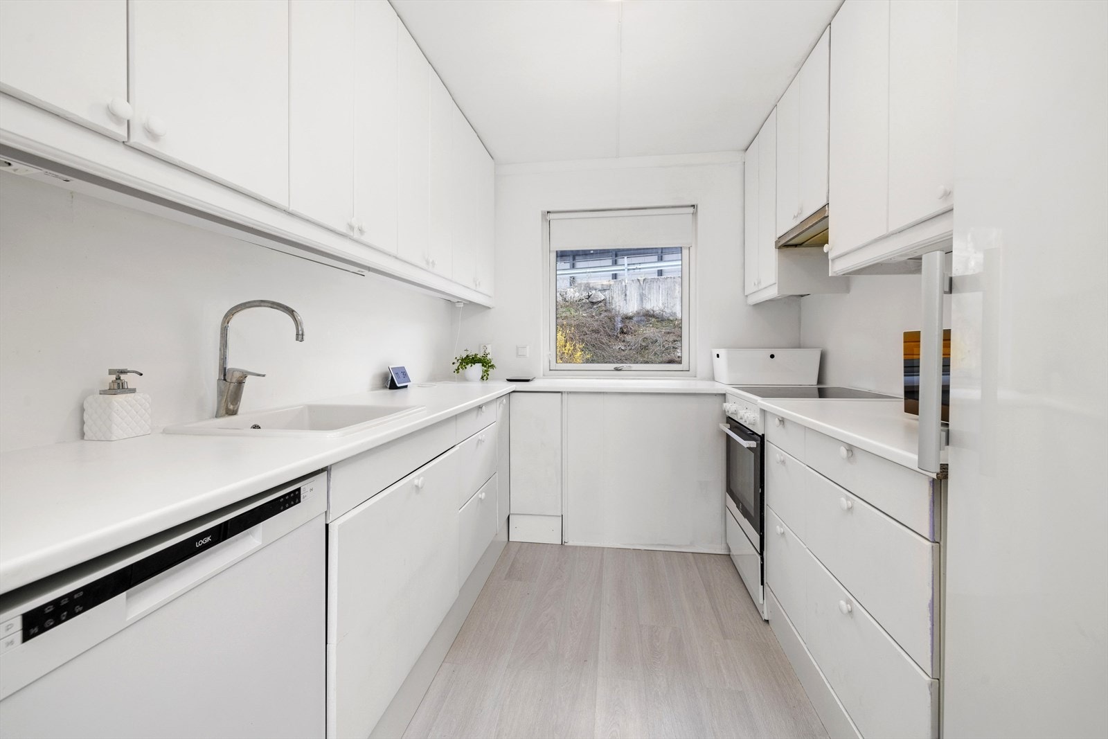 Lyst kjøkken med god benkeplass og godt med skaper Galleribilde