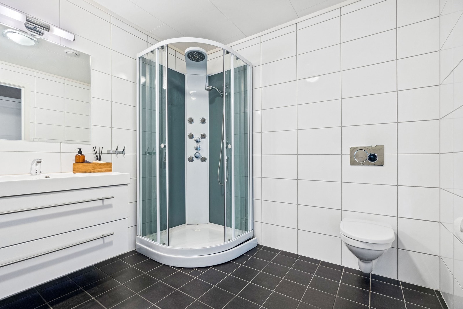 Badet er på 7,8 kvm. Det er helfliset med vegghengt toalett og dusjkabinett. Galleribilde