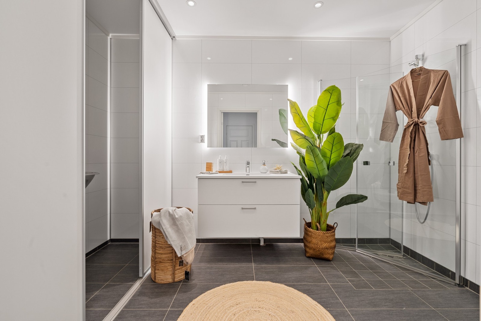 Lekkert bad i moderne utførelse med fliser på gulv og baderomsplater med flisemønster på veggene. Galleribilde