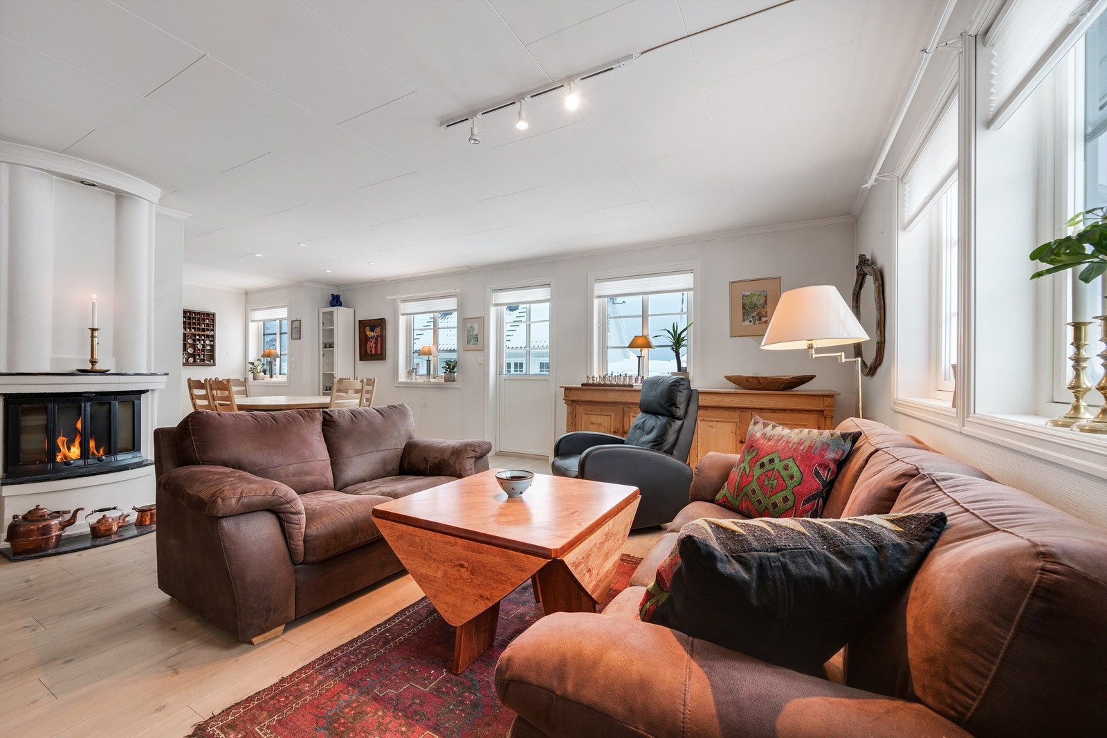 Stue med peisovn og åpen løsning til kjøkkenet Galleribilde