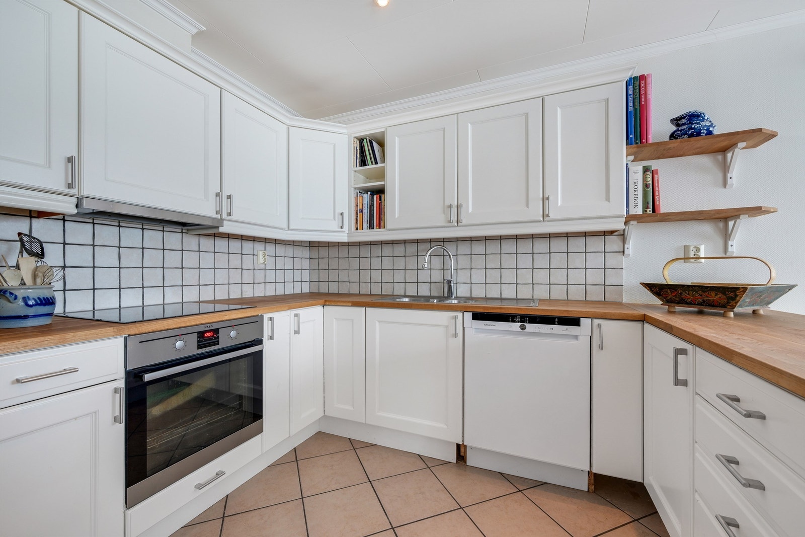 Kjøkkenet har en innredning i malte profilerte fronter og integrert keramisk platetopp og stekeovn Galleribilde