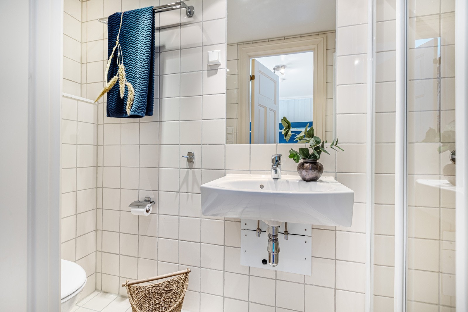 Bad/wc med adkomst fra gangen er innredet med servant, speil og belysning, veggmontert wc, dusj med Galleribilde