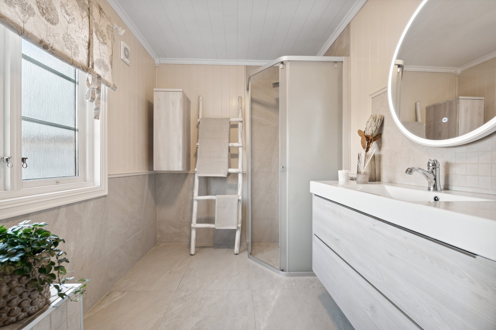 Videre er badet innredet med baderomsinnredning med nedfelt servant og speil, toalett og dusjhjørne. Galleribilde