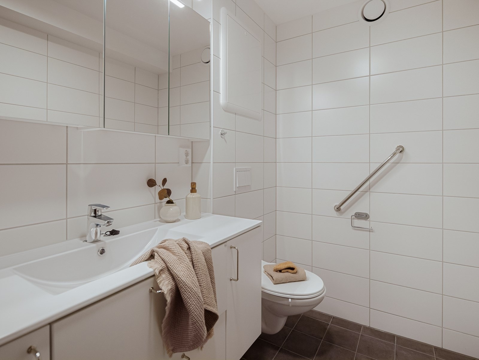 Det er utstyrt med vegghengt toalett, dusj med innfellbare glassvegger, speilskap og baderomsinnredning med servant. Galleribilde