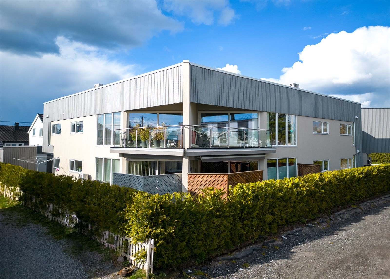 Rundt blokken løper en smal rand av gressplen, innrammet av hekk mot vei og naboer. Galleribilde
