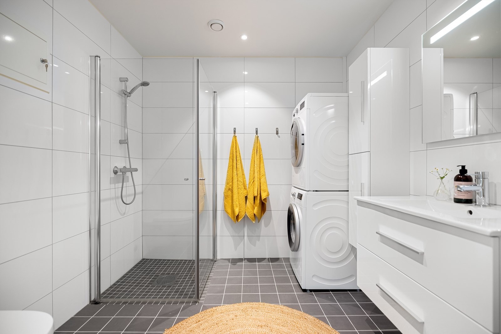 Badet er flislagt på vegger og gulv og har nedsenket dusjsone med glassvegger. Galleribilde