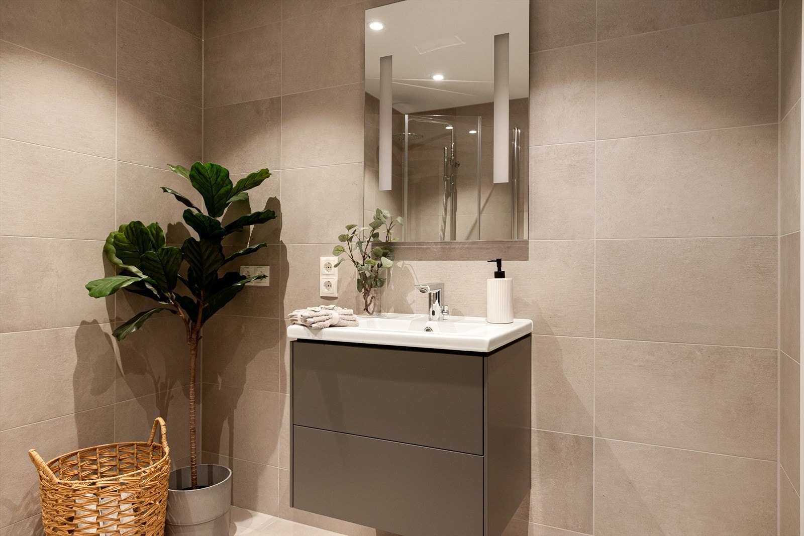 Baderomsinnredningen består av stilren, matt sort overflate med to skuffer, servant med armatur i krom utførelse og vegghengt speil med belysning. Galleribilde