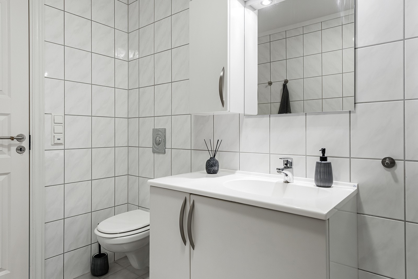 Av innredning er det dusjhjørne med skyvedører i fastkarm, vegghengt toalett, opplegg for vaskemaskin og et stilrent baderomsmøblement. Galleribilde