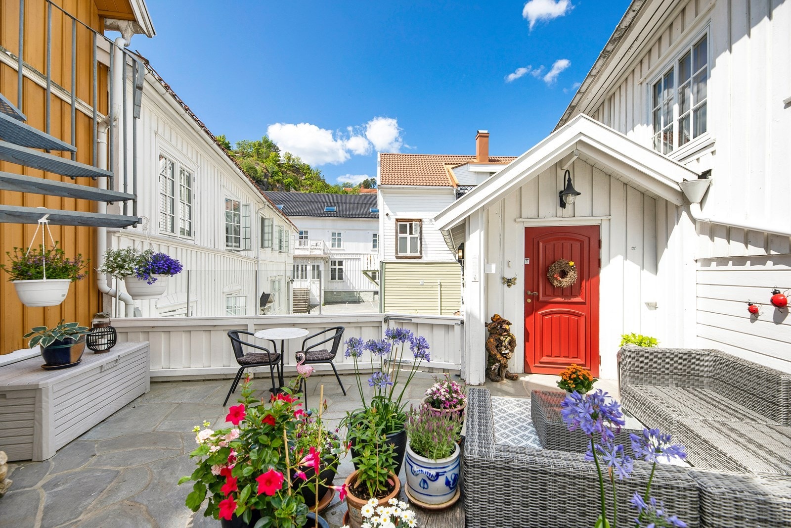 Inngangspartiet har en sjarmerende stil med hvitmalt kledning, belysning og en rødmalt ytterdør. Galleribilde