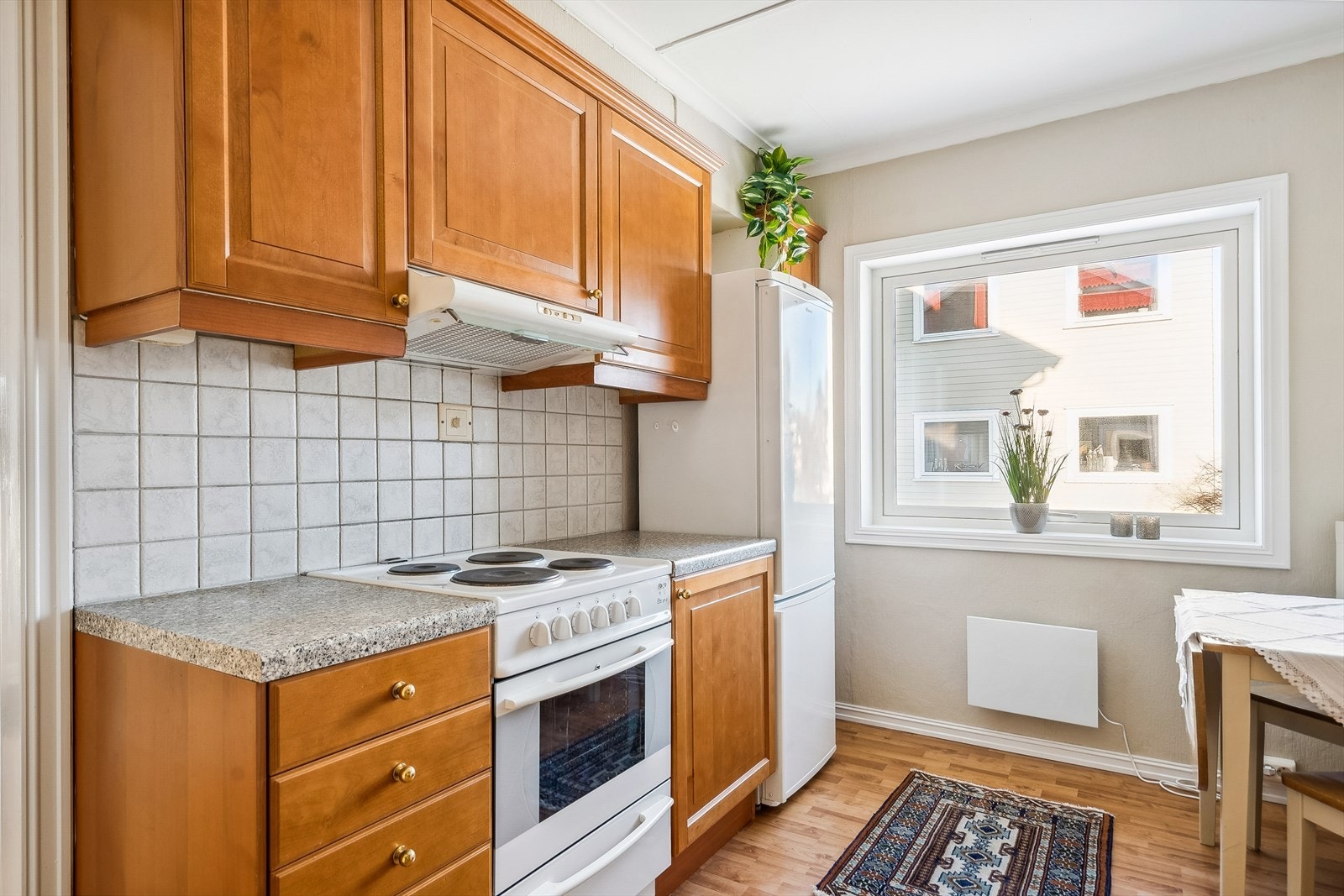 Kjøkken med profilerte fronter fra ca 2001 i følge tidligere takst. Benkeplaten er av laminat med nedfelt kum. Hvitevarer som komfyr, oppvaskmaskin og kjøl/frys. Kjøkkenventilator med avtrekk ut. Komfyrvakt er montert. Lys fungerer ikke. Galleribilde