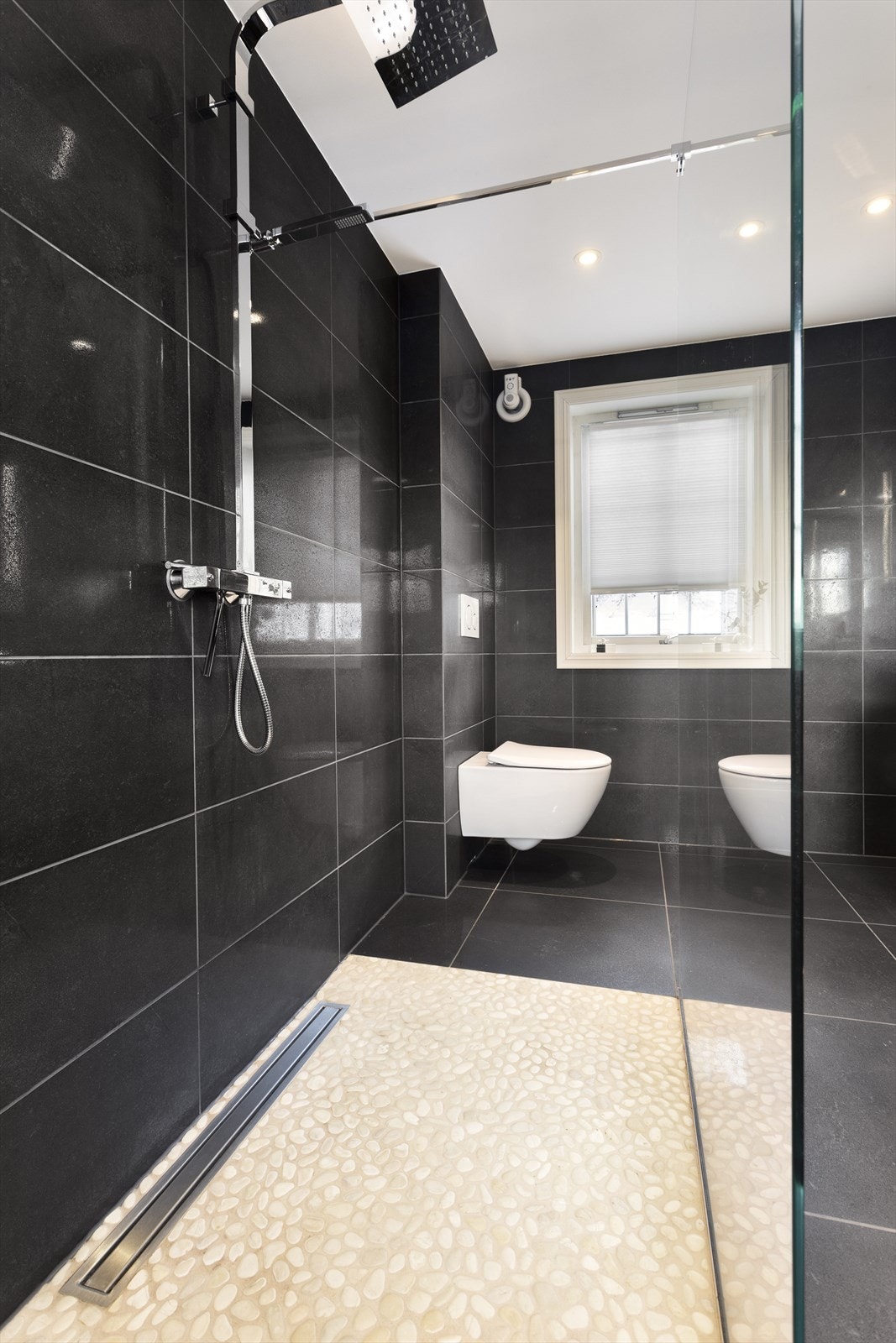 Badet har dusj med dusjvegg av glass og regnfallsdusj Galleribilde