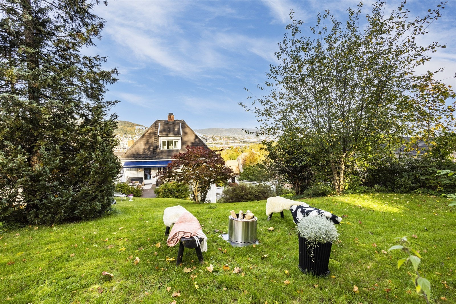 Skrånende tomt som er pent opparbeidet med gressplen, trær, prydbusker og diverse beplantninger Galleribilde
