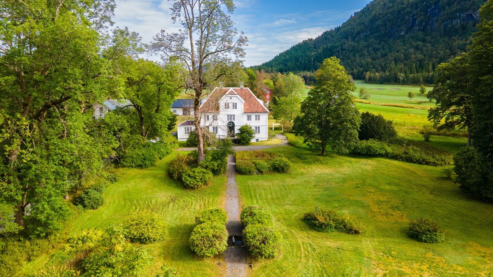 Hovedhus med parkanlegg og golfbanen i bakgrunnen Galleribilde