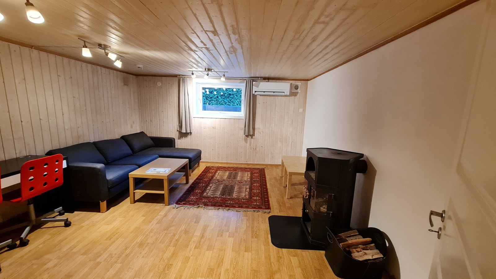 Stue med sofa, bord, varmepumpe, peisovn, og nytt vindu. Galleribilde