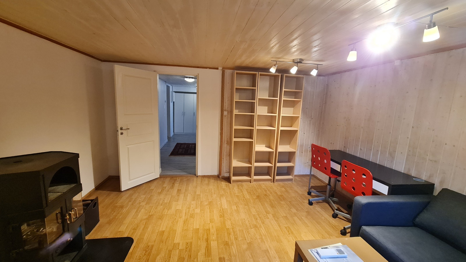 Stue med bokhyller, enkel kontorpult, peisovn med vedkurv Galleribilde