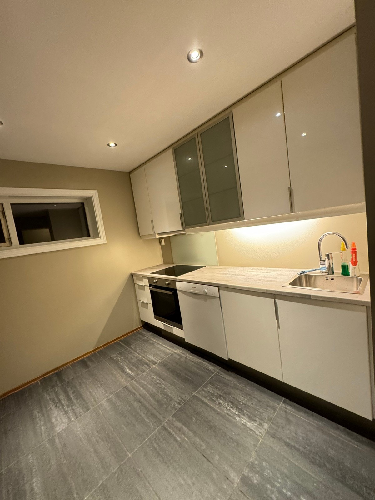 Kjøkken med høyglanset kjøkken og fliser på gulv med varmekabler. Galleribilde