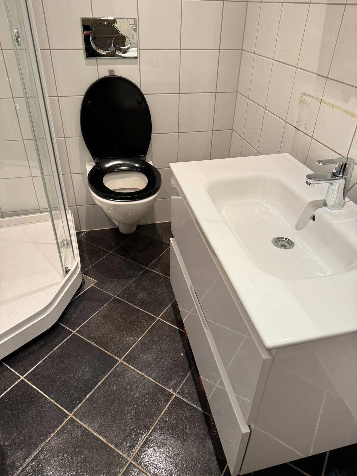 Bad med dusjkabinett, vegghengt toalett og fliser med varmekabler. Galleribilde