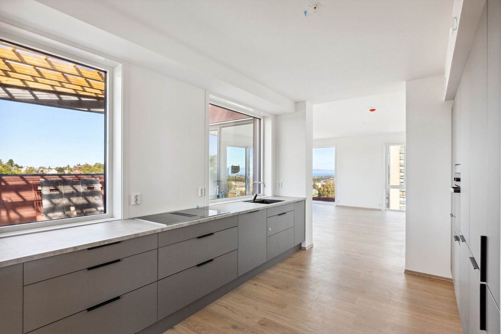 Innholdsrikt kjøkken fra HTH med fronter i Base mørk sand, integrerte hvitevarer og platetopp med integrert lufting. Her vil man få gode oppbevaringsmuligheter og en herlig utsikt ut mot den private takterrassen. Galleribilde